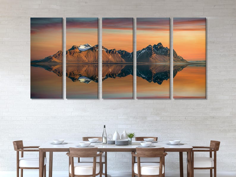 Sunset mountain landscape with snow-capped peaks and mirrored reflections on calm water