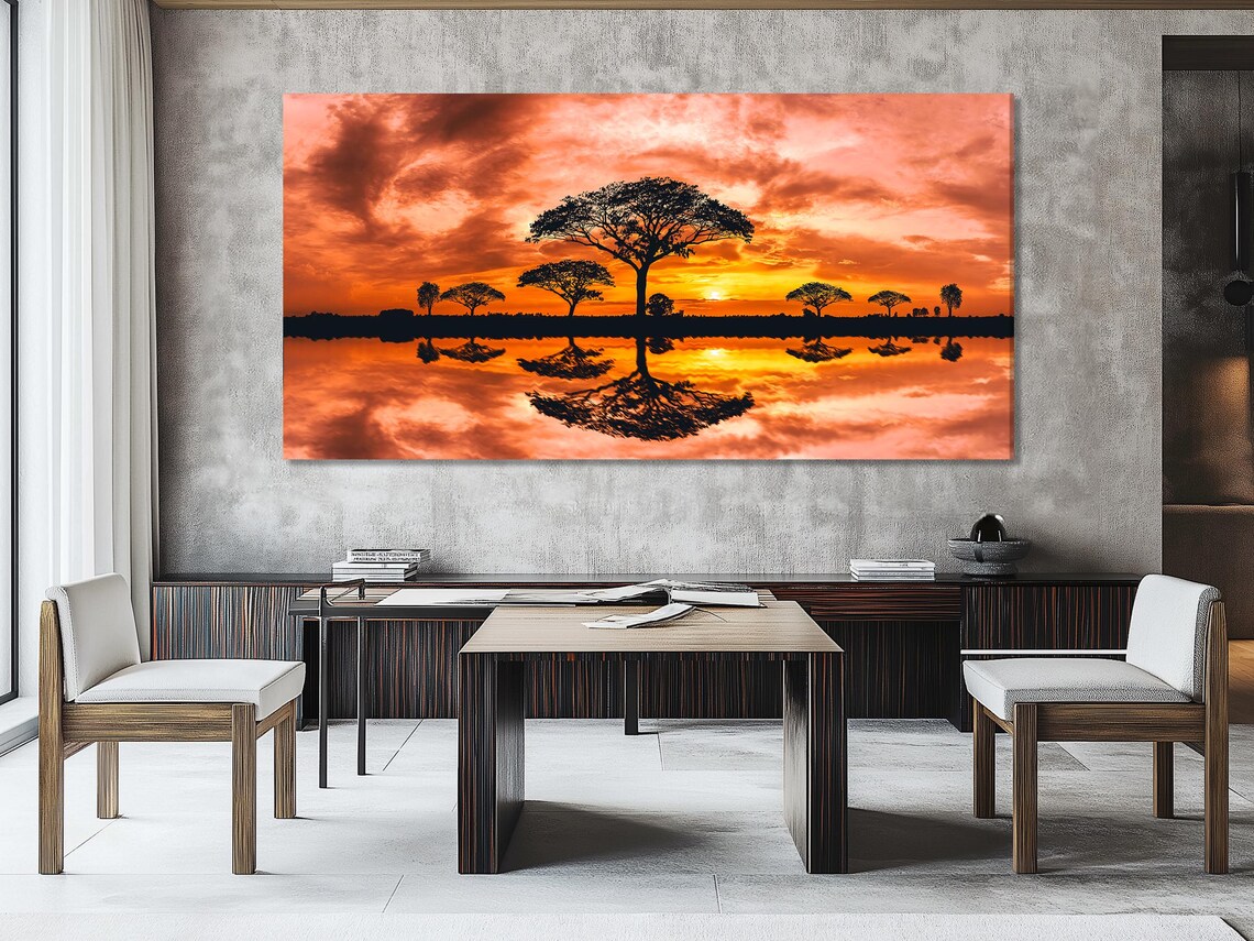Sunset landscape with orange clouds, dark tree silhouettes and reflective water detail view