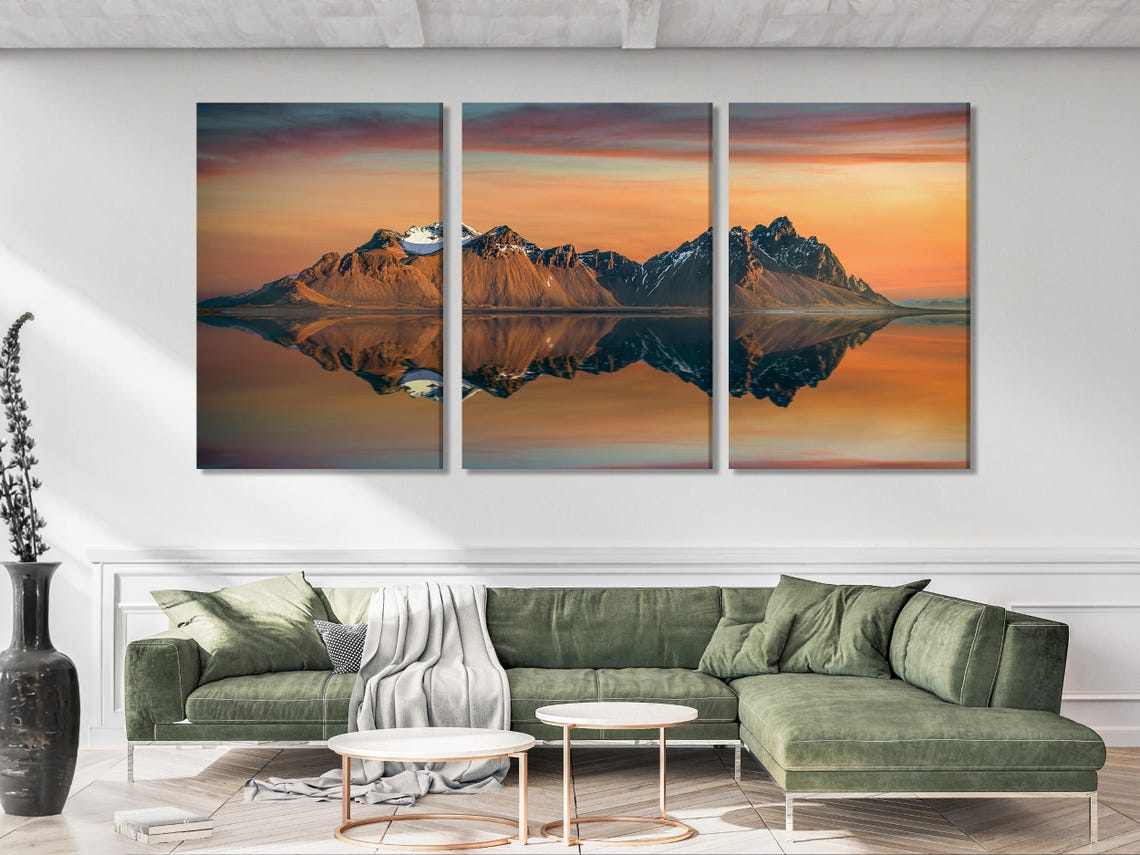 Dining table scene with a five-panel sunset mountain artwork on a white brick wall