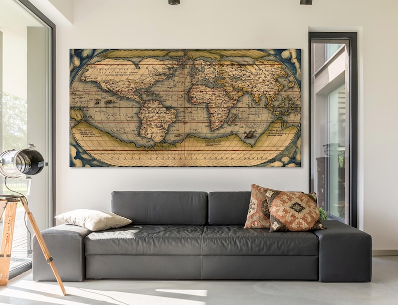 K&ouml;nnte beinhalten: Ein Vintage-Weltkarten-Druck in braunen, gelben und blauen T&ouml;nen mit Text in einem verblassten, antiken Stil. Die Karte ist gerahmt und h&auml;ngt an einer Wand &uuml;ber einem grauen Sofa mit Kissen.
