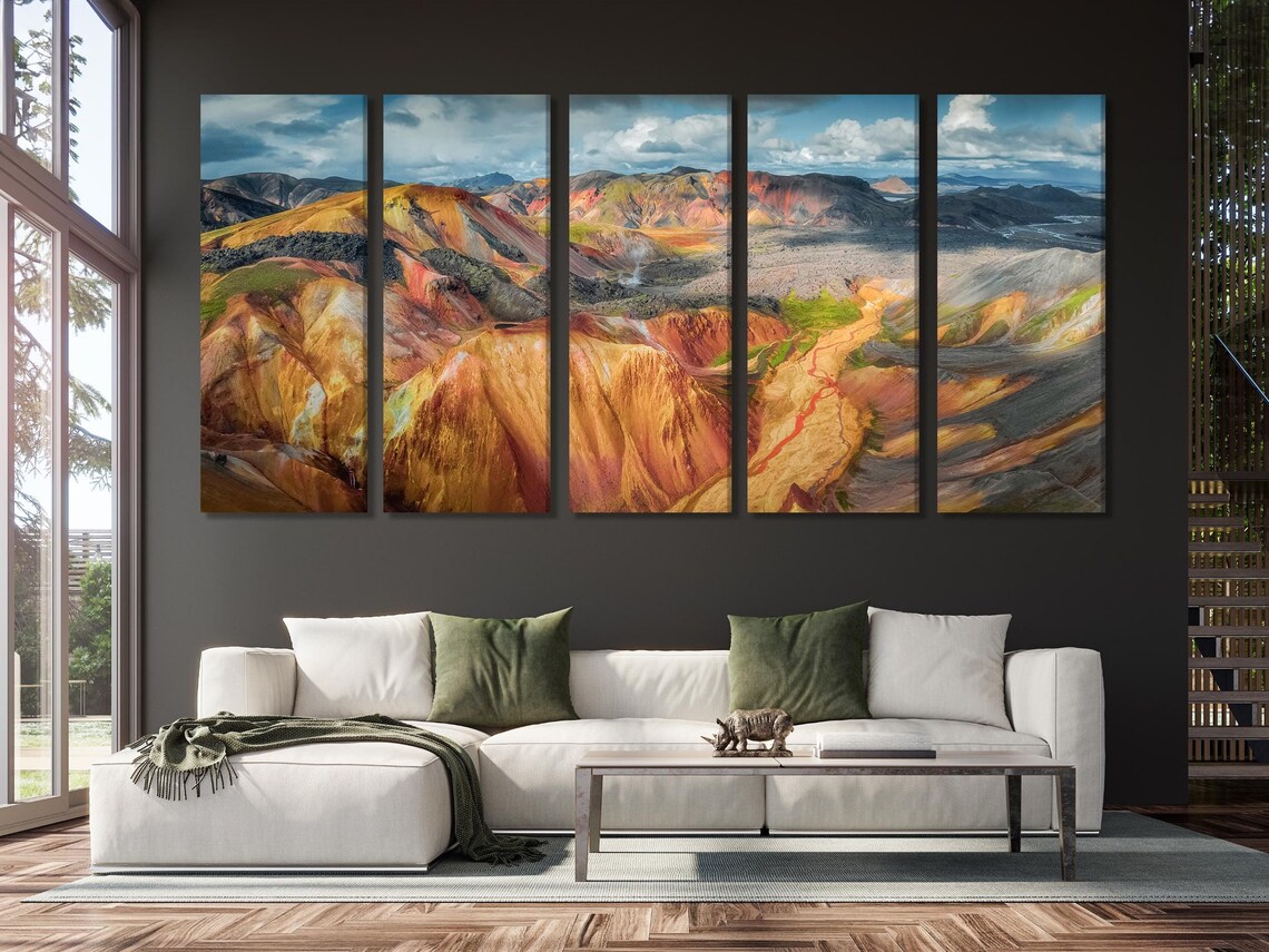 Mountain landscape artwork above a sofa with teal cushions and neutral decor
