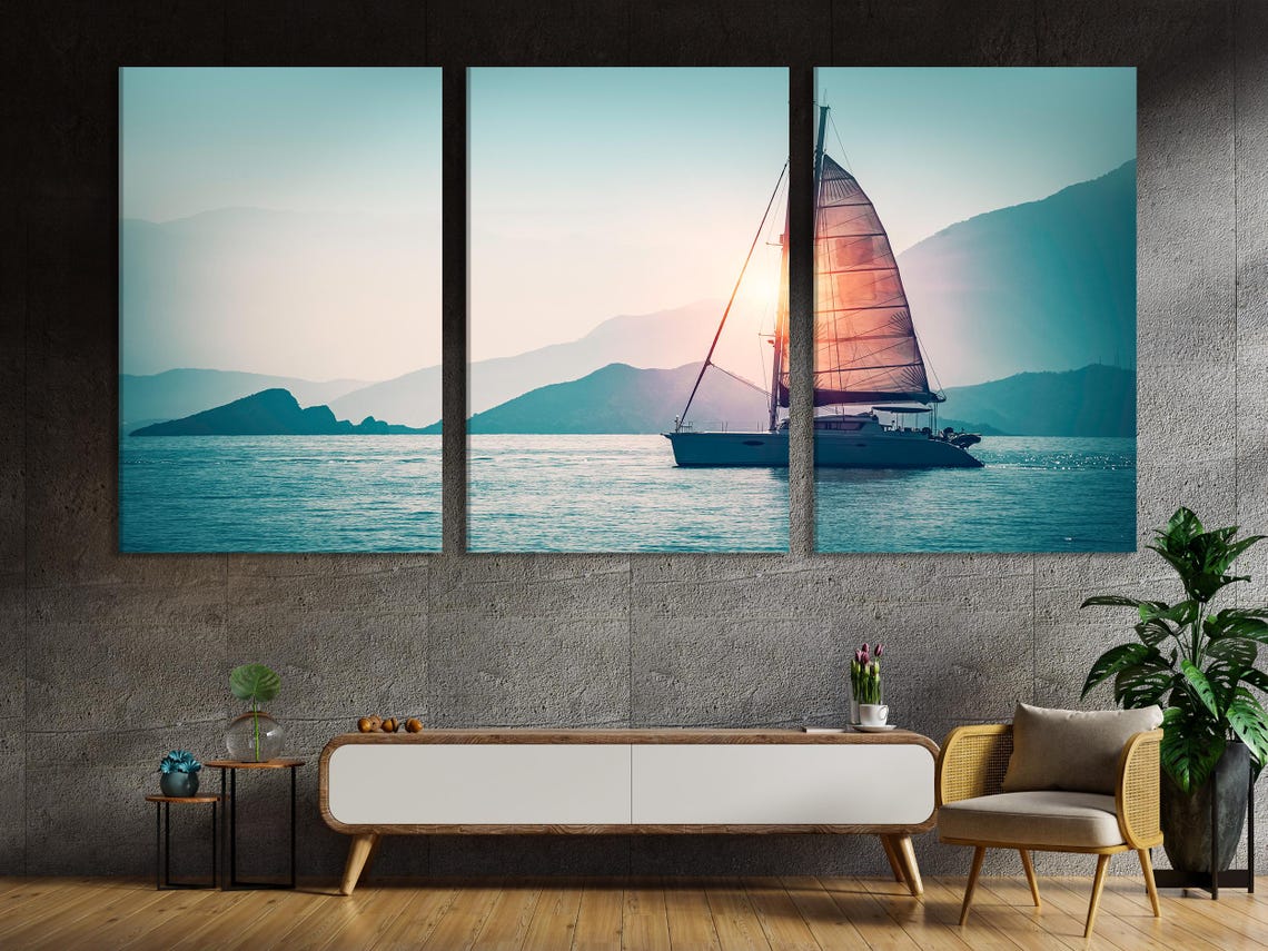 Sunset sailboat seascape with warm glow on sails, calm blue water and distant mountains detail view