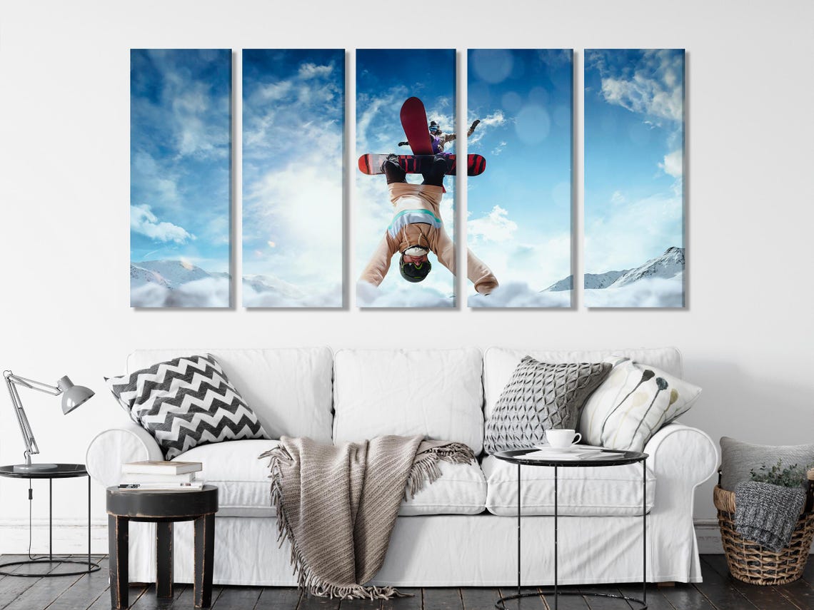 Snowboarder mid-flip against a bright blue sky with snowy mountains in the background detail view
