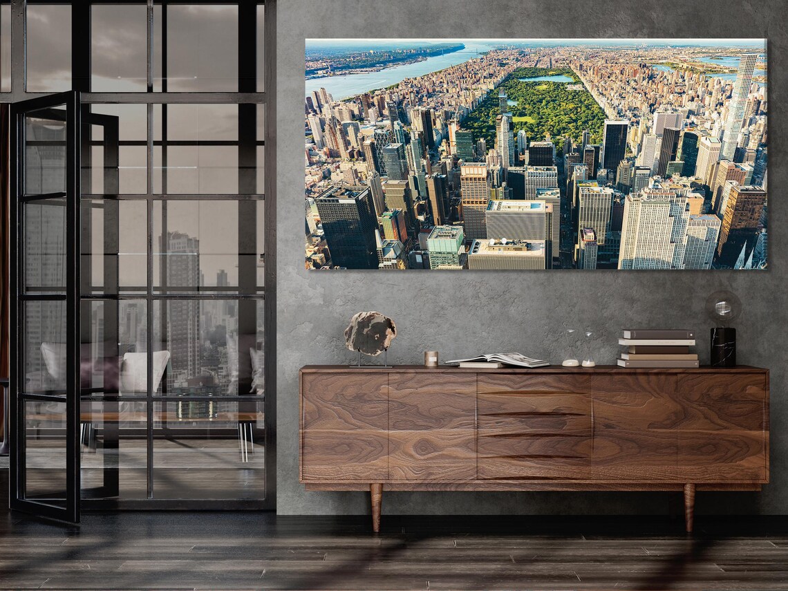 Room mockup showing three panels of a New York skyline aerial cityscape above a sofa