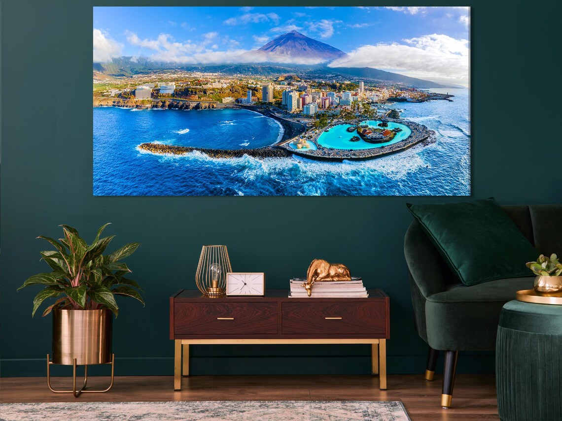 Room mockup showing three-panel aerial coastline artwork above a blue sofa
