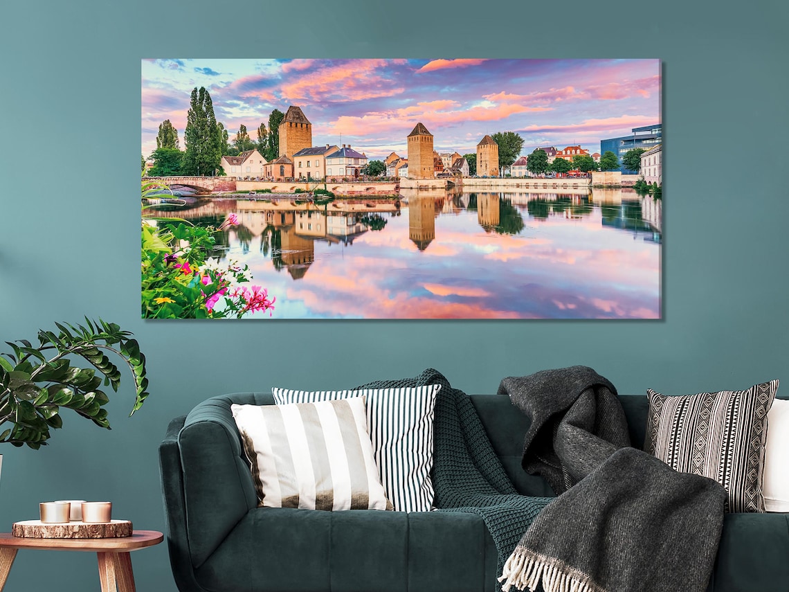 A three-panel sunset cityscape shows historic stone towers and buildings reflected in a calm river, with a pink-orange sky and green trees detail view