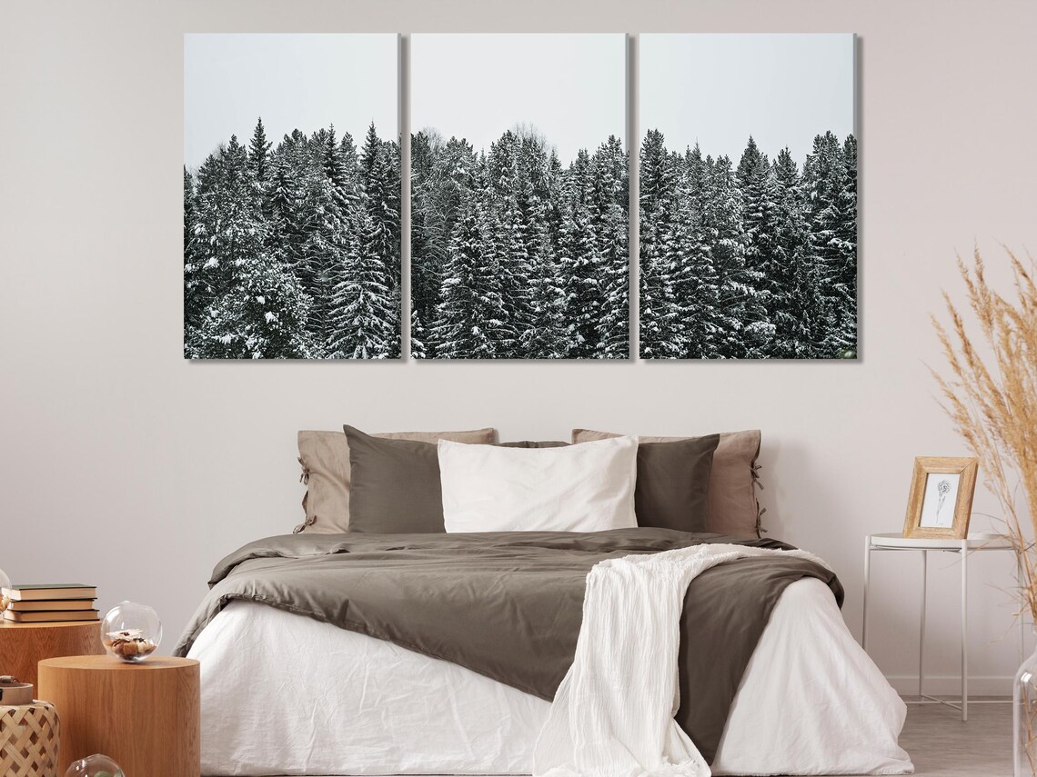A living room mockup with dark snowy pine forest wall artwork above a sofa