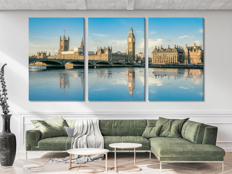 London skyline artwork featuring a tall clock tower, buildings, a bridge, and their reflections in a river under a blue sky