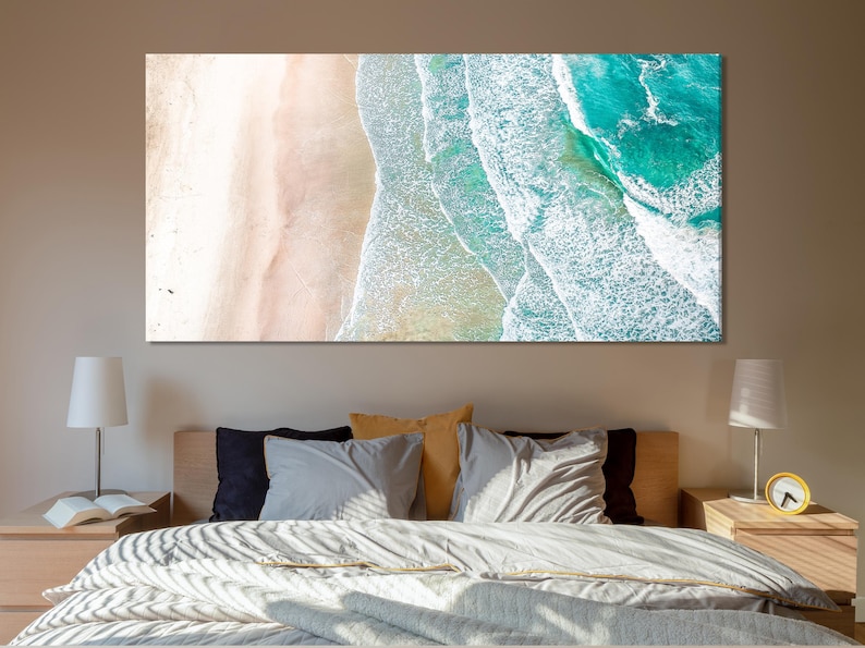 Aerial view of beach sand and turquoise ocean waves with white foamy surf