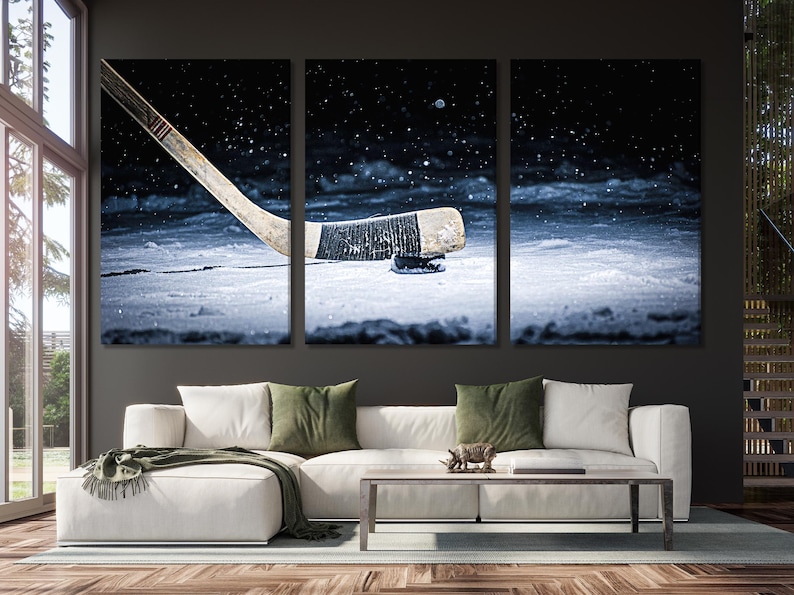 Snowy ice hockey scene with a hockey stick angled across the frame and a puck on bright ice, falling snow in a dark night sky