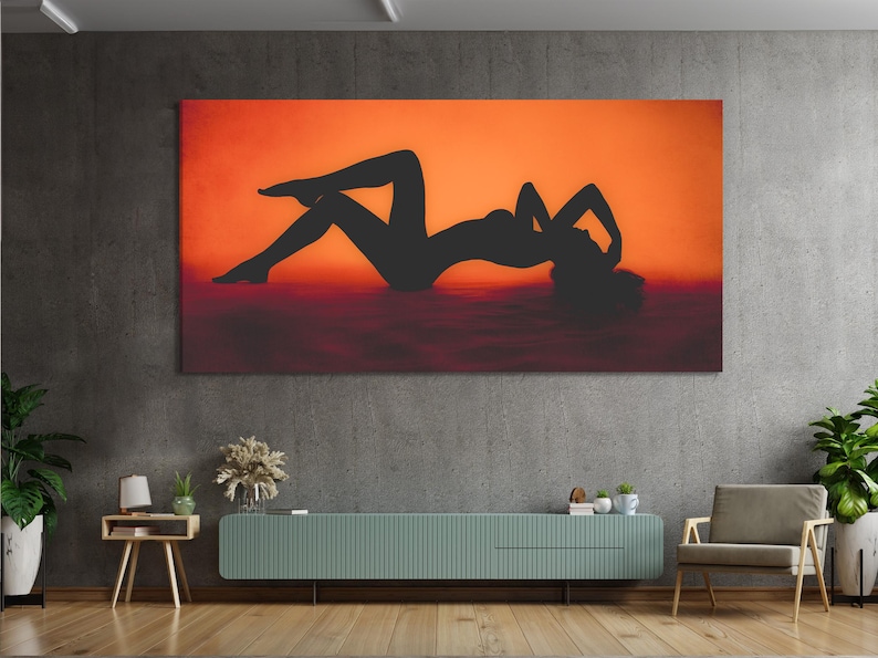 Black reclining female silhouette against an orange sunset with dark reflective water