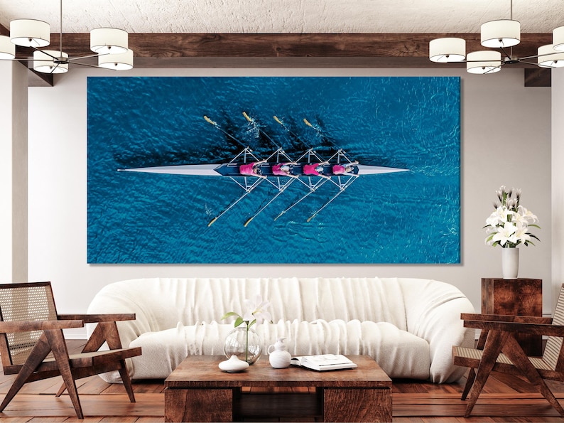 Aerial view of a rowing boat on bright blue rippling water with rowers and diagonal oars