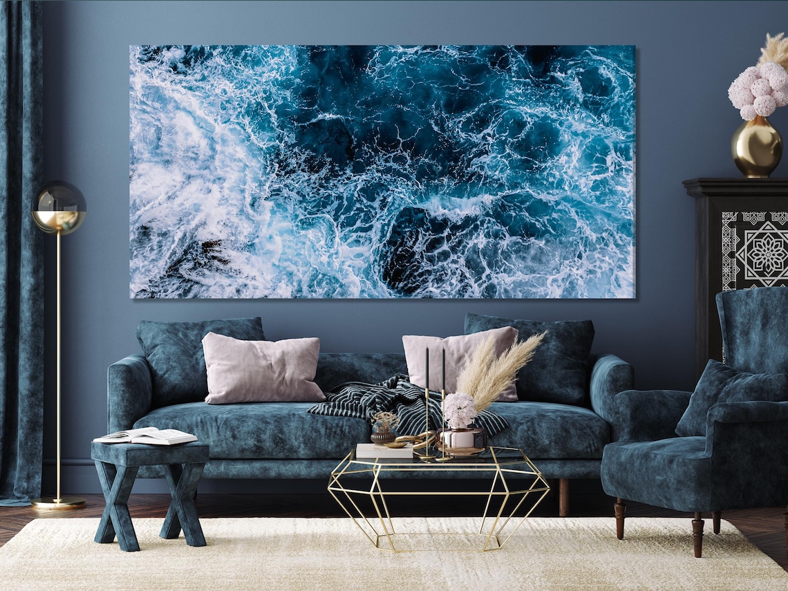 Ocean wave wall artwork above a sofa and table in a bright interior