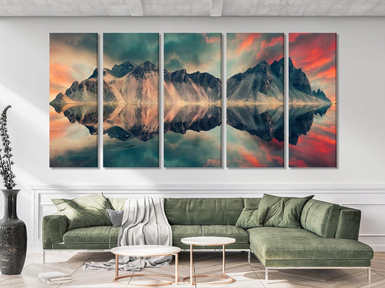 Split mountain landscape artwork with dark peaks, clouded sky and warm sunset reflections in water