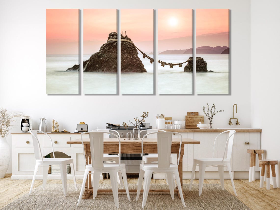 A sunset seascape shows two rocky islands connected by a rope with small posts, set against soft pink-orange skies and pale misty water detail view