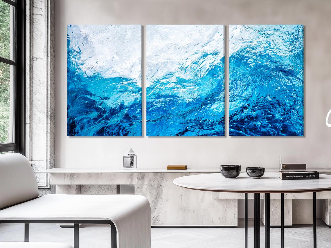 Ocean waves artwork on a white wall above a blue armchair and sofa
