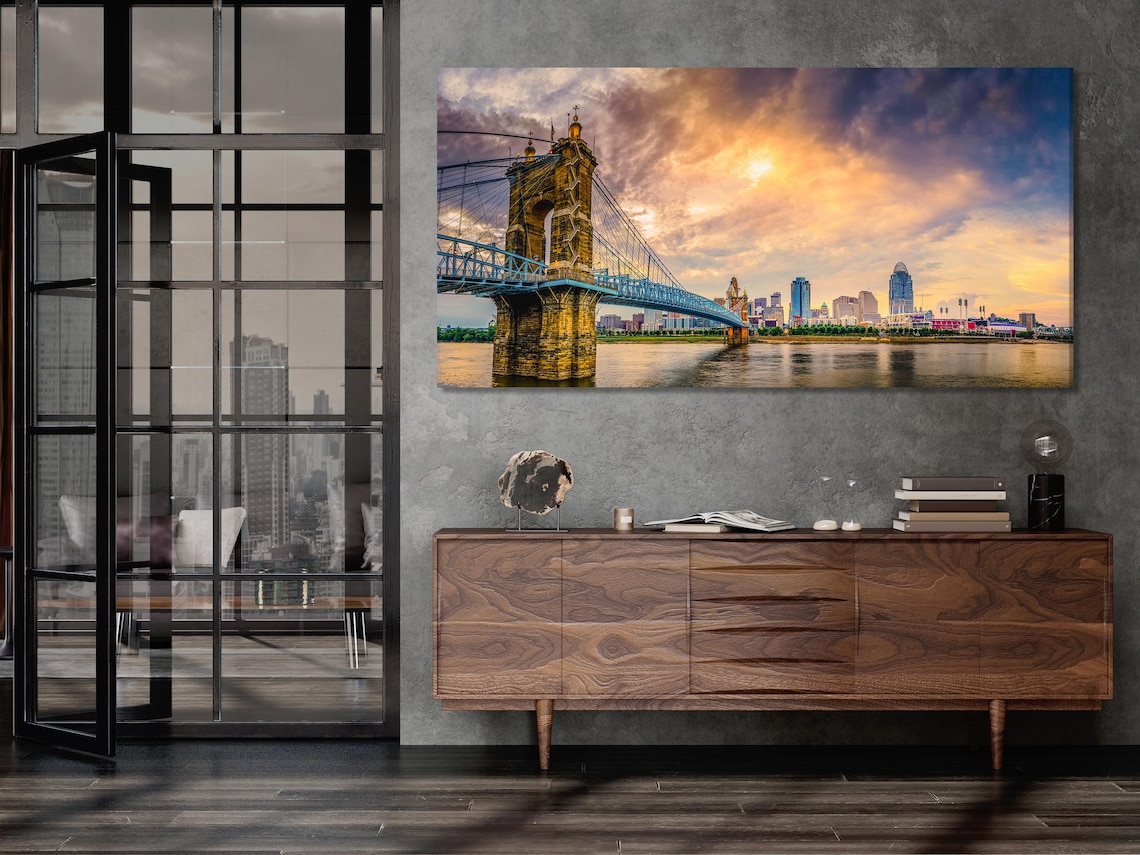 Dusk suspension bridge and city skyline over a river with warm orange sky and deep blue clouds detail view