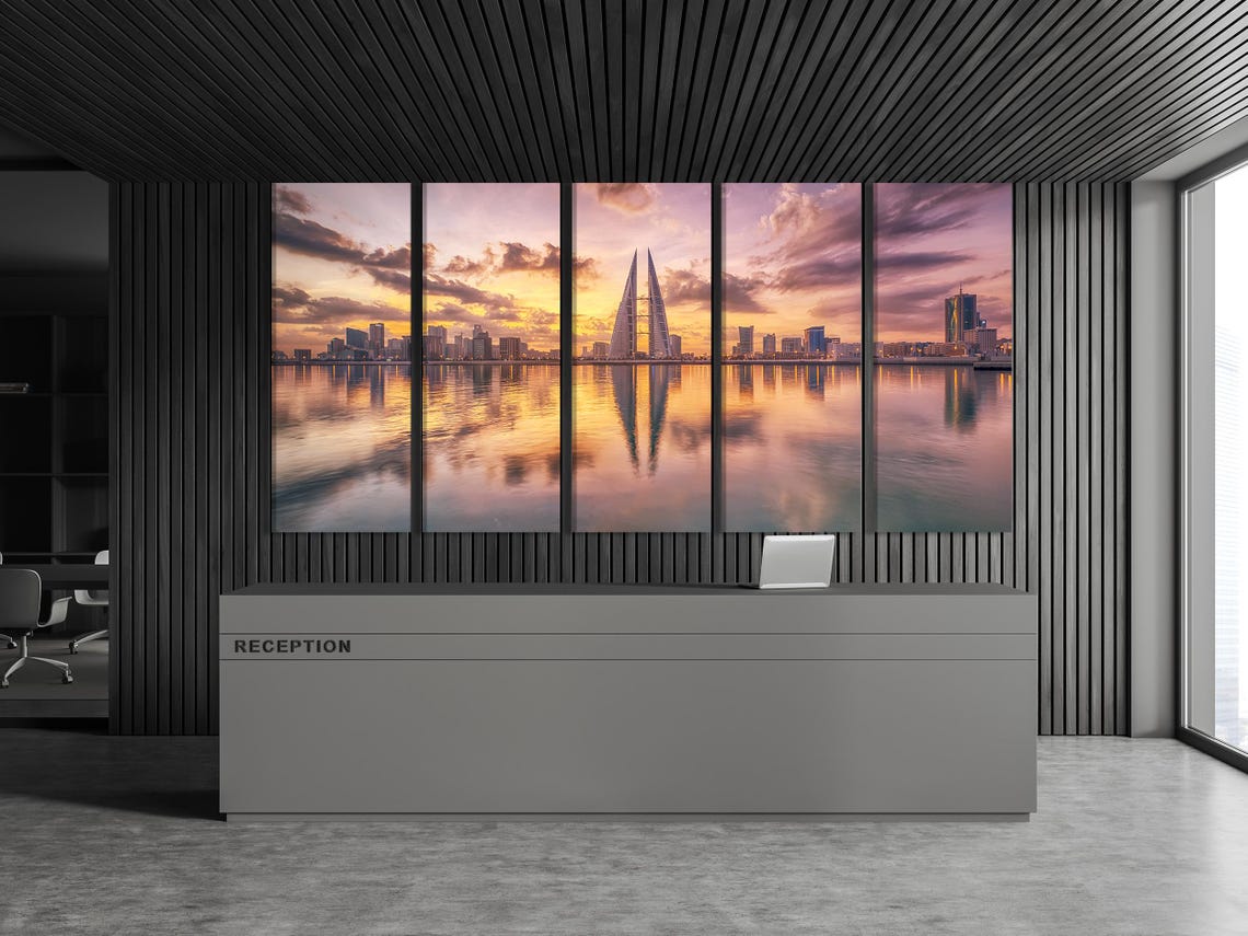 Sunset city skyline with a tall pointed tower and reflections on calm water detail view