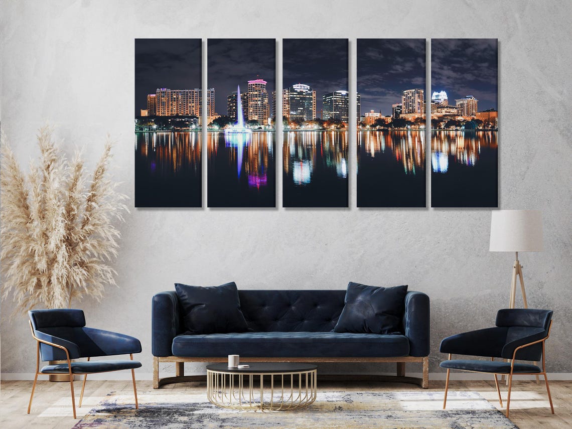 Three-panel night cityscape with illuminated buildings and reflections on dark lake water detail view