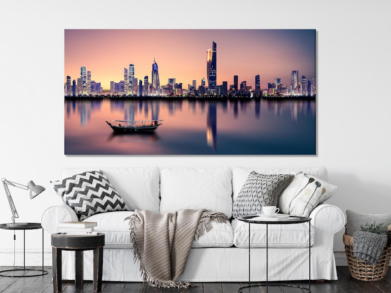 Twilight city skyline with illuminated buildings reflected in calm water and a dark boat silhouette