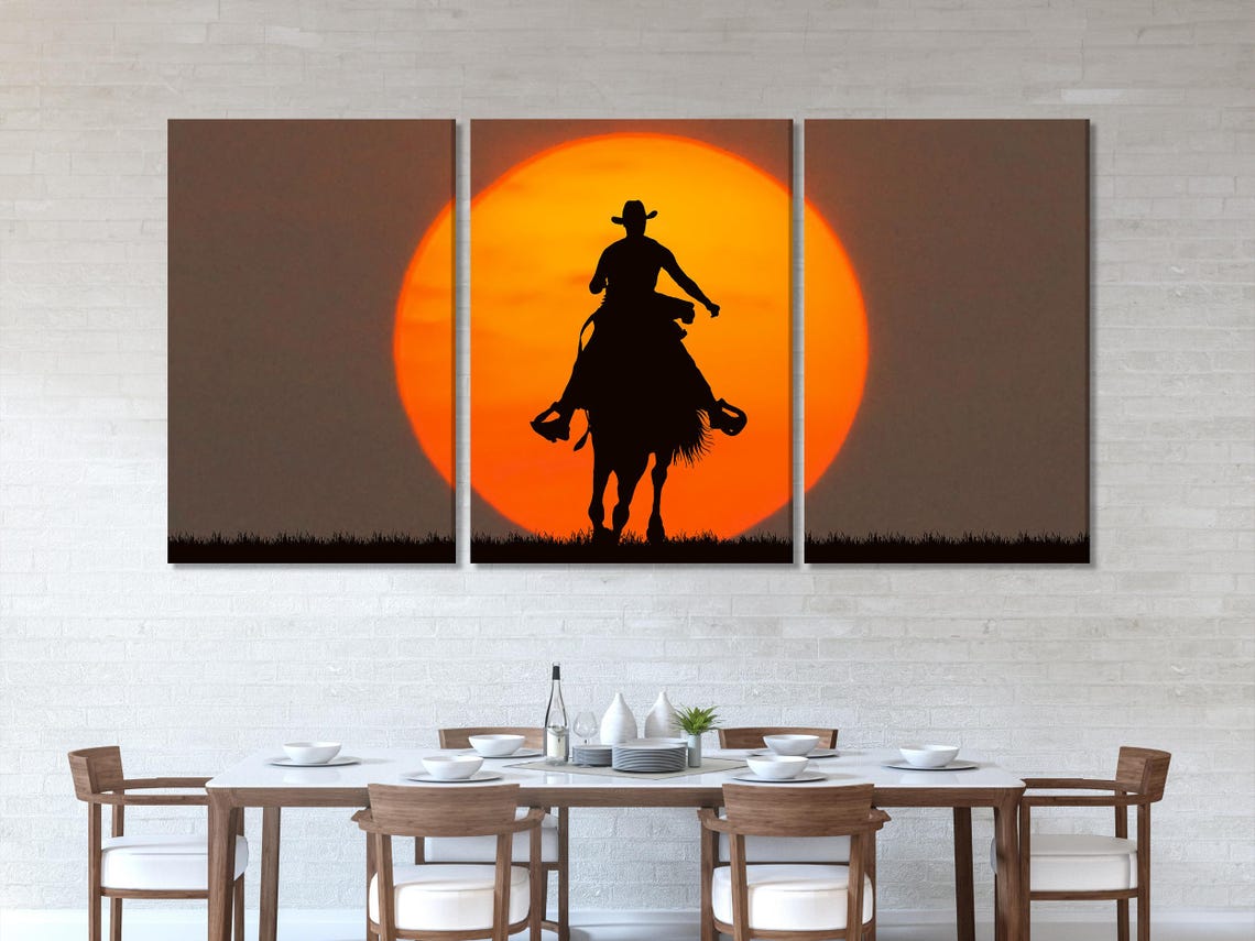 Black cowboy riding a horse silhouette beneath a glowing orange sun with dark grass detail view