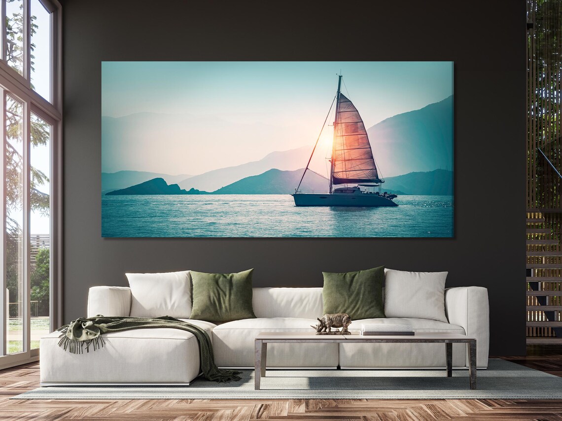 Sunset sailboat seascape with warm glow on sails, calm blue water and distant mountains detail view