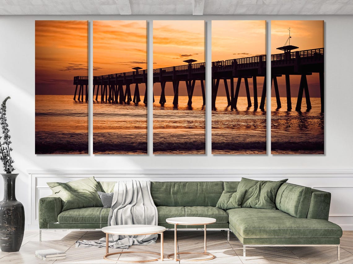 Artwork of a sunset ocean pier scene displayed in a living room