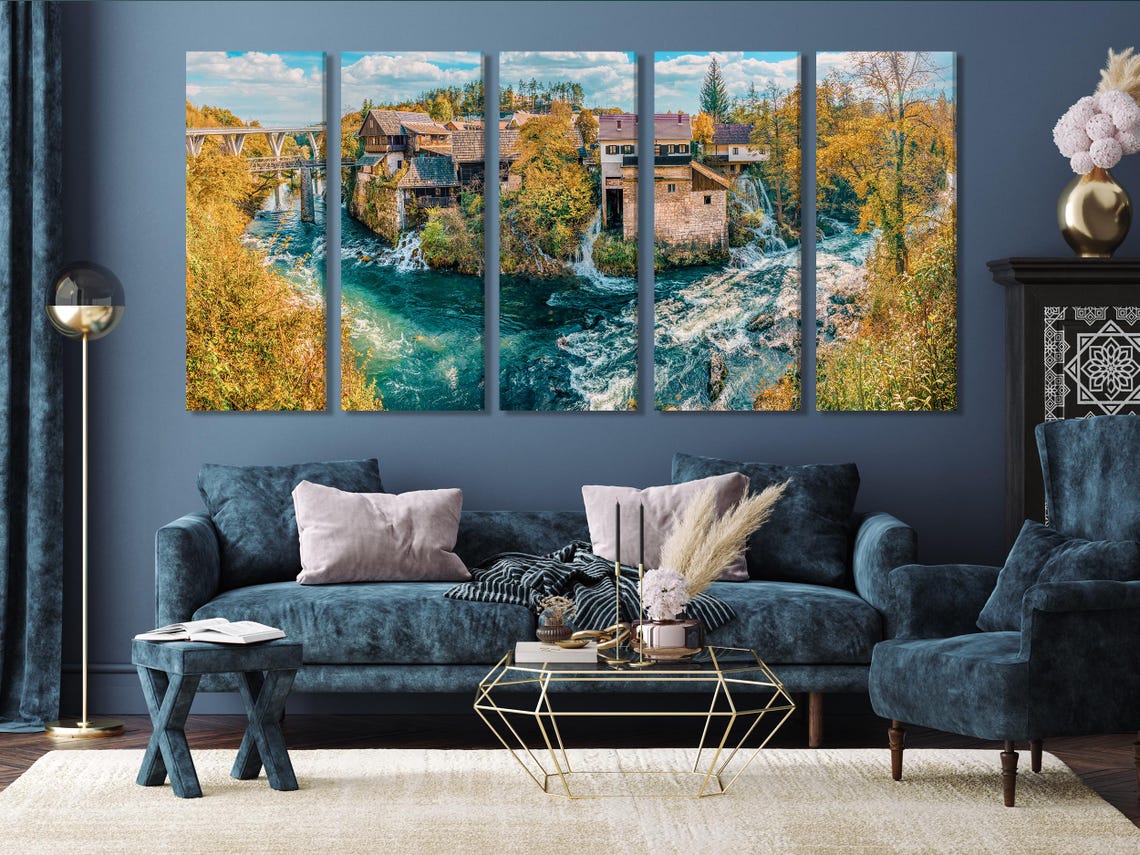 Wide river landscape with turquoise water, waterfalls, autumn trees and a village under a blue sky detail view