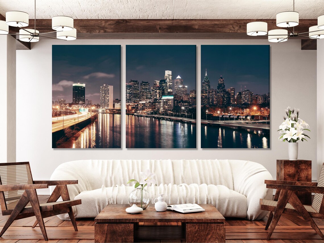 A night city skyline stretches across a wide river, with glowing building lights and shimmering reflections under a deep blue sky detail view