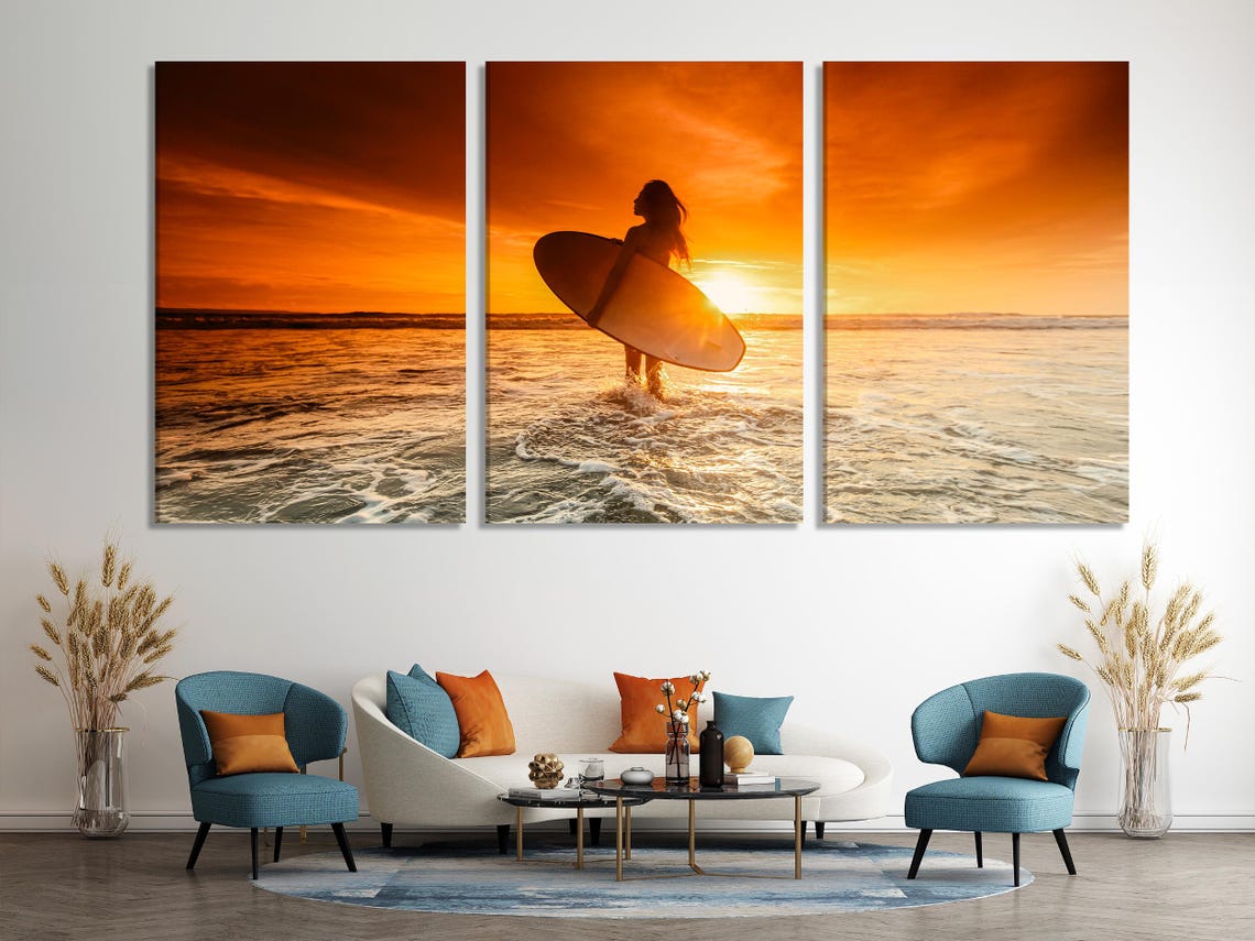 Sunset beach scene with a silhouetted surfer holding a surfboard in front of golden ocean waves detail view