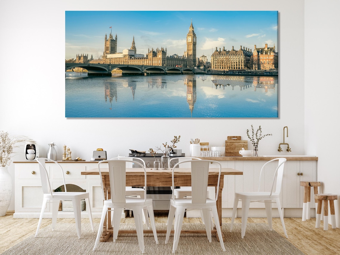 London skyline artwork featuring a tall clock tower, buildings, a bridge, and their reflections in a river under a blue sky detail view