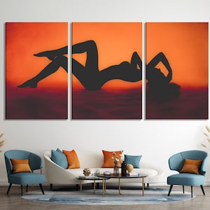 Triptych wall art featuring a silhouette of a person in a reclining pose against a sunset-colored background. The artwork is composed of three panels, each depicting a portion of the figure. The color palette consists of warm oranges, reds, and deep browns, creating a dramatic and sensual mood. The silhouette is rendered in black, providing a stark contrast against the vibrant background. The overall style is modern and minimalist, suitable for contemporary interiors.