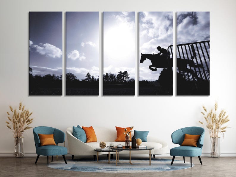 Black silhouette of a jumping horse and rider against a cloudy monochrome sky