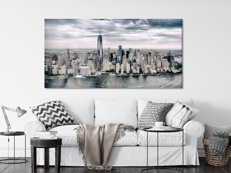 Aerial city skyline with a tall central tower, skyscrapers and a waterfront under cloudy grey skies