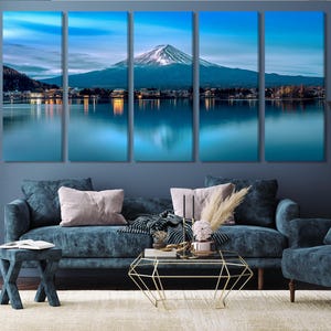 May include: A five-panel canvas print depicting a scenic view of Mount Fuji reflected in a still lake. The mountain is snow-capped and the sky is a soft blue with clouds. The lake is a deep blue and the surrounding landscape is green.