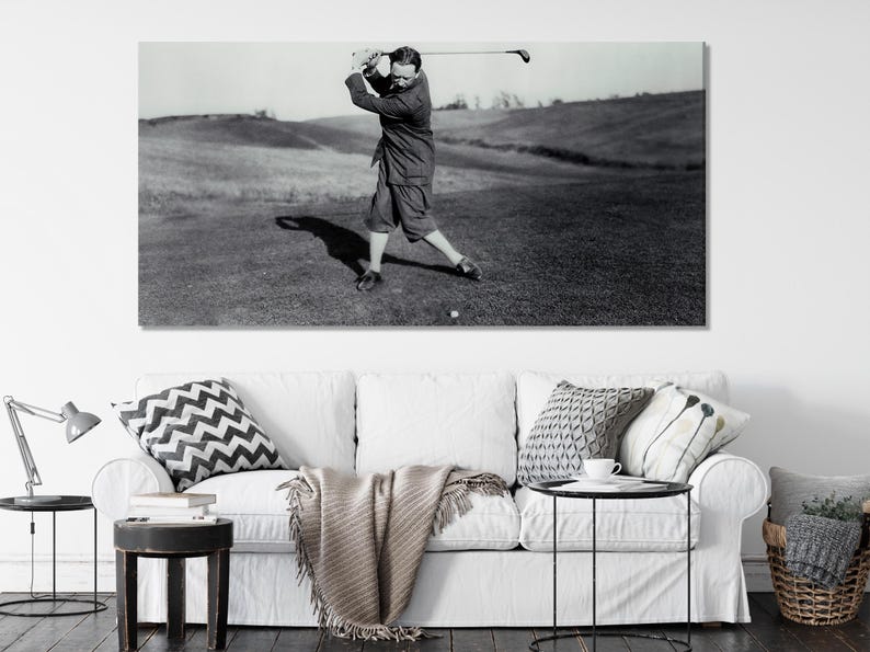 Black-and-white golfer mid-swing on a fairway with a long shadow