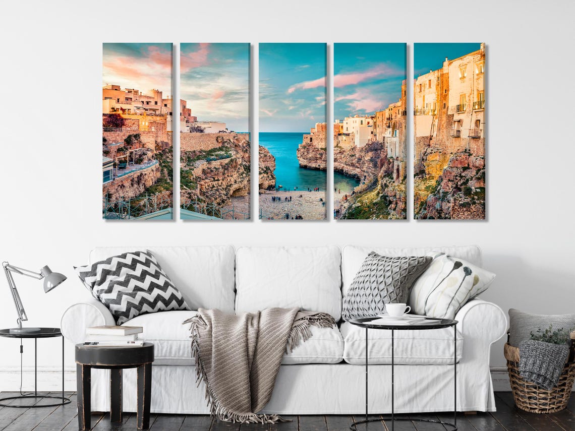 Sunlit cliffside town overlooking a sheltered bay with turquoise blue water and a pastel sky detail view