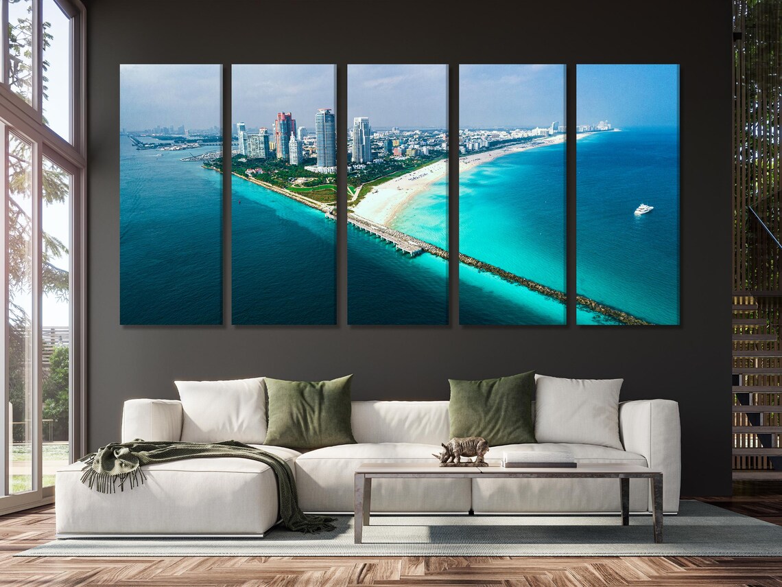 Room mockup with a sofa and artwork panels showing an aerial coastline scene
