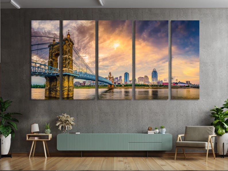 Dusk suspension bridge and city skyline over a river with warm orange sky and deep blue clouds
