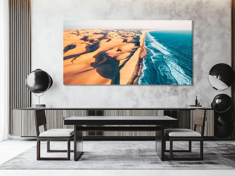Aerial view of golden desert dunes meeting bright blue ocean waves along a curving shoreline