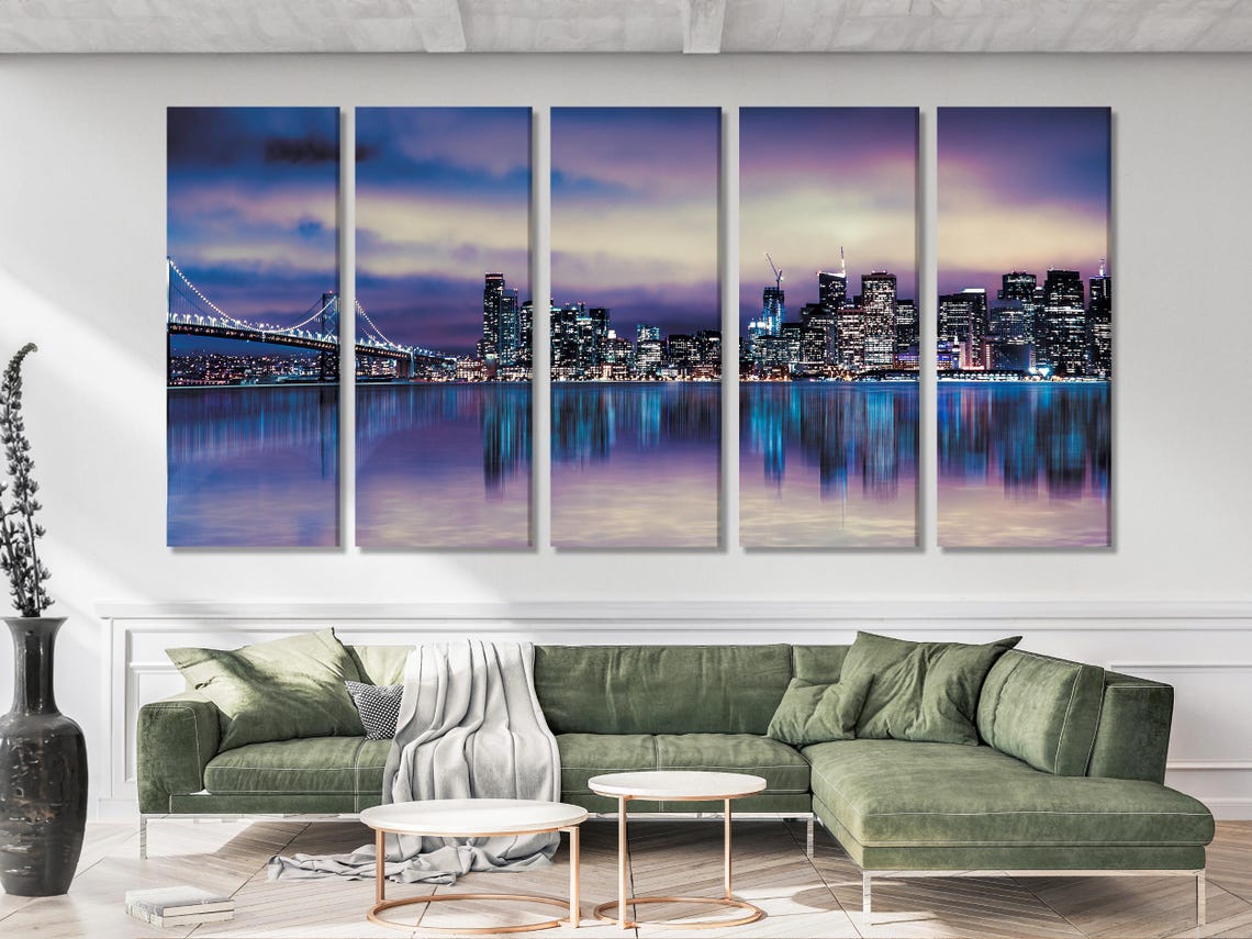 A night cityscape skyline glows in purples and blues, with a lit bridge, calm reflective water and a clouded sky detail view