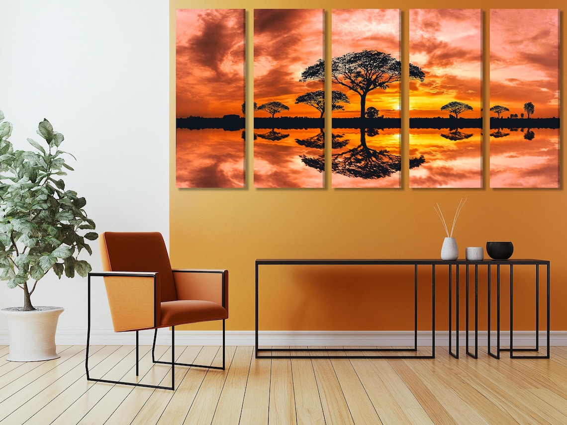 Sunset landscape with orange clouds, dark tree silhouettes and reflective water detail view