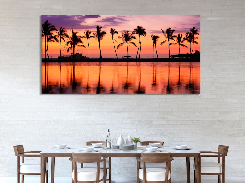 Tropical sunset with silhouetted palm trees and boats, reflected in calm water