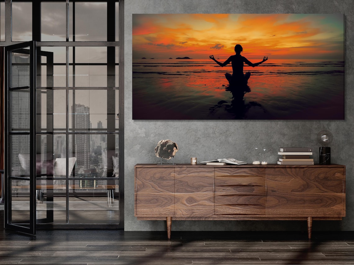 Room mockup with a three-panel sunset meditation artwork on a grey wall above a sofa area