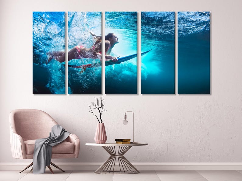 Five-panel canvas print depicting two women underwater, surfing on a surfboard. The vibrant blue water is filled with bubbles and sunlight. The women are wearing bikinis and are positioned dynamically on the board. The overall theme is aquatic sports and action photography. The image is suitable for home or office decor.
