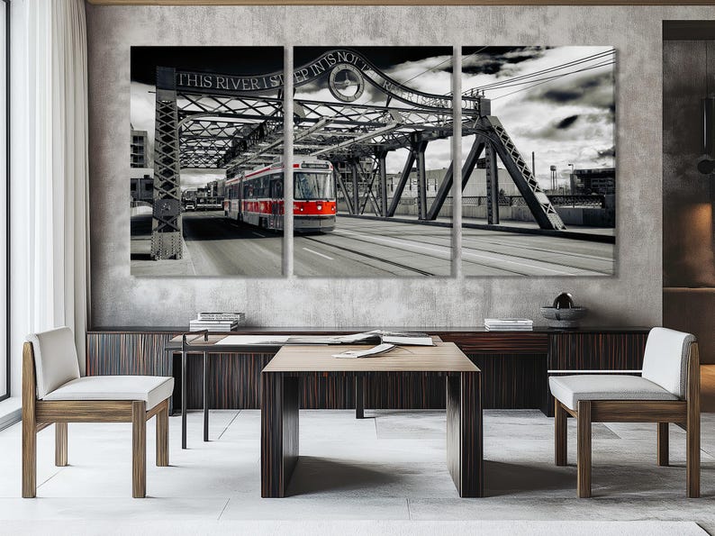 Black-and-white steel bridge with a red-fronted streetcar under cloudy skies