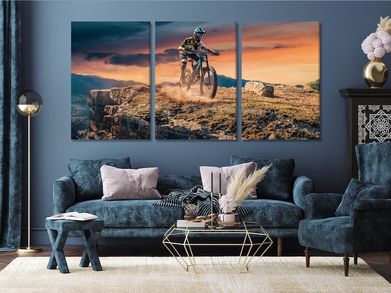 Mountain biker riding across rocky terrain at sunset with an orange sky and deep blue shadows