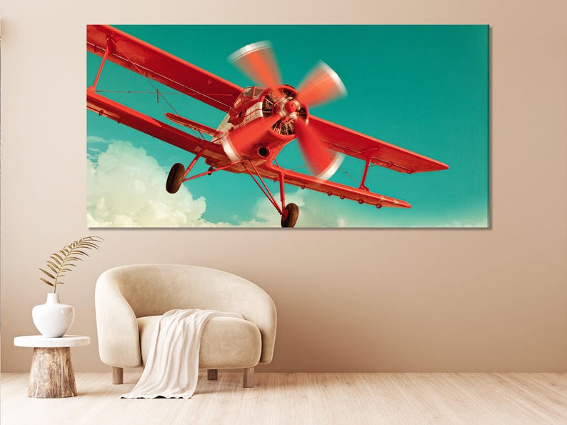 Red biplane aircraft flying through a turquoise sky with pale clouds and motion-blurred propellers