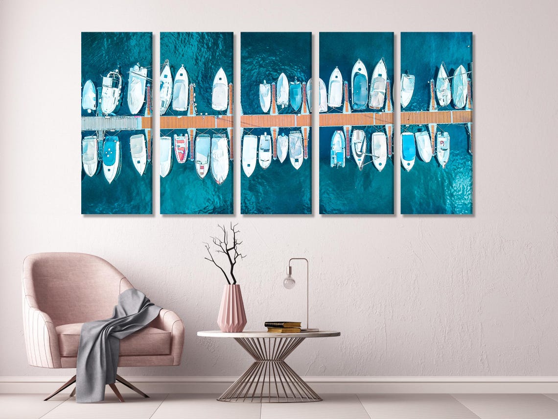 Aerial view of rows of white yachts docked along a pier in deep teal water detail view