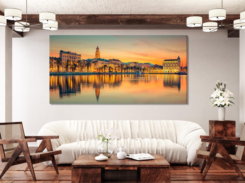A sunlit waterfront cityscape at golden hour shows palm-lined buildings and a calm reflection across the water, with bright orange and teal tones